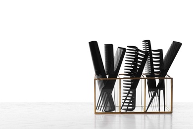 Photo of Set of professional hair combs in holder on white wooden table