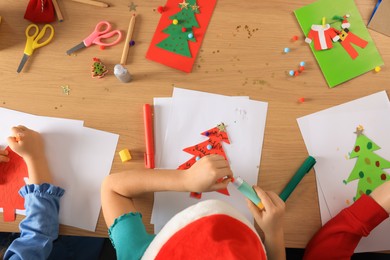 Little children making beautiful Christmas greeting cards at table, top view