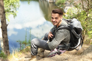 Young man with cute cat near lake. Camping season