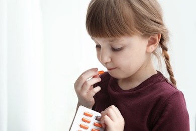 Photo of Little child taking pill indoors, space for text. Danger of medicament intoxication