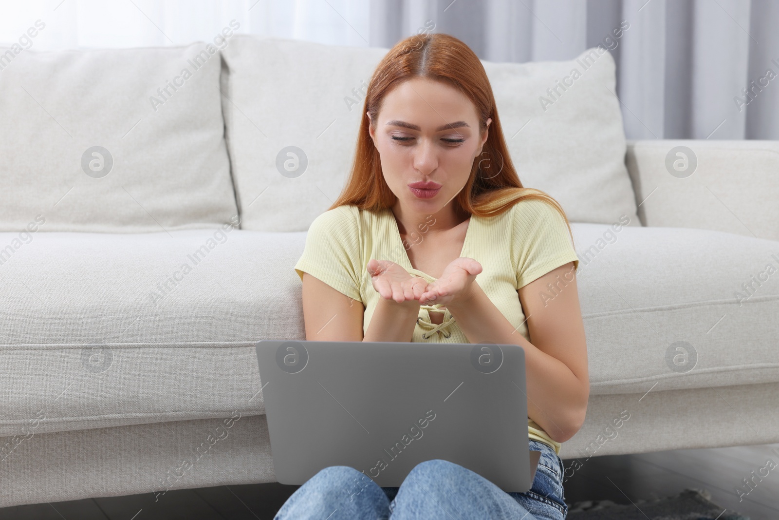 Photo of Woman blowing kiss during video chat via laptop at home. Long-distance relationship