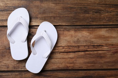 Photo of Stylish flip flops on wooden background, flat lay. Space for text