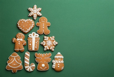 Christmas tree shape made of delicious gingerbread cookies on green background, flat lay. Space for text