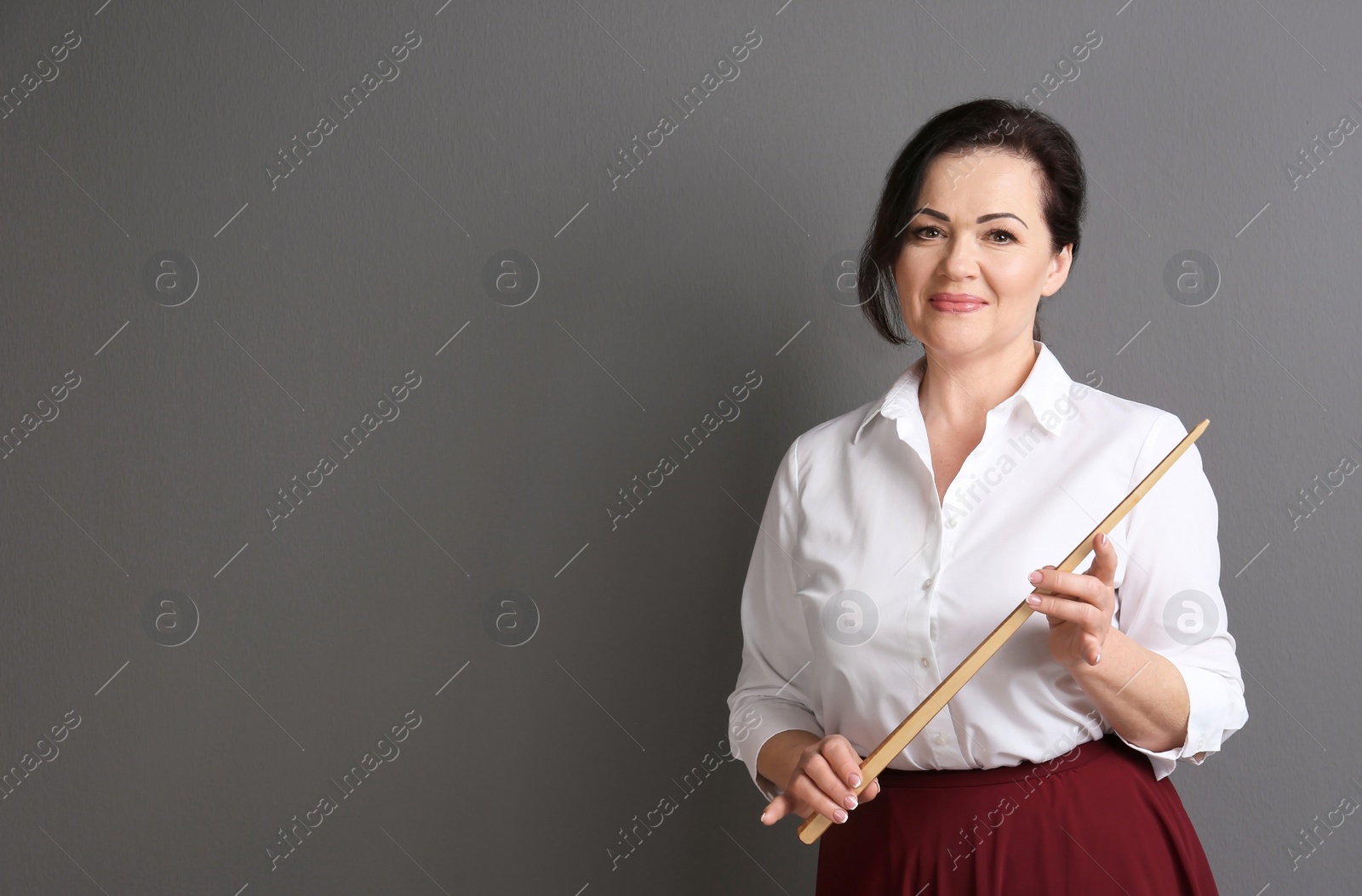 Photo of Portrait of female teacher with pointer on grey background