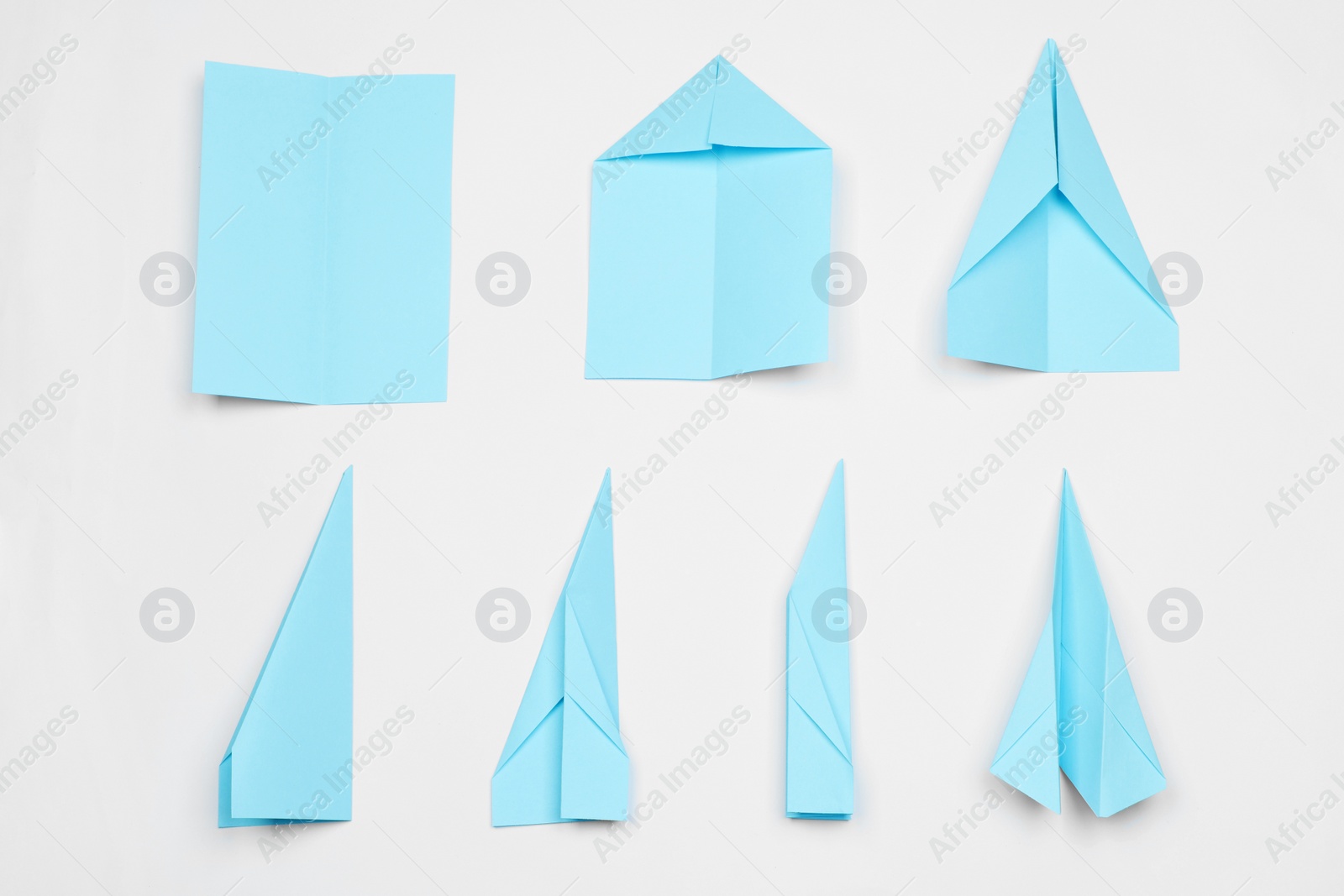 Photo of Making paper plane step by step. Instruction on white table, flat lay