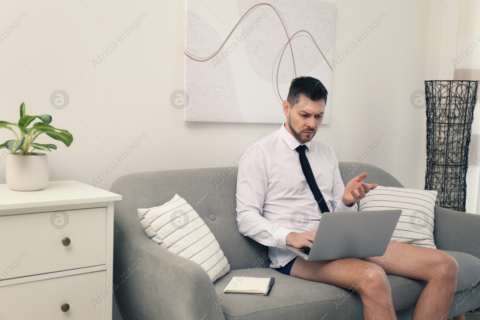 Photo of Businessman wearing shirt and underwear during video call at home