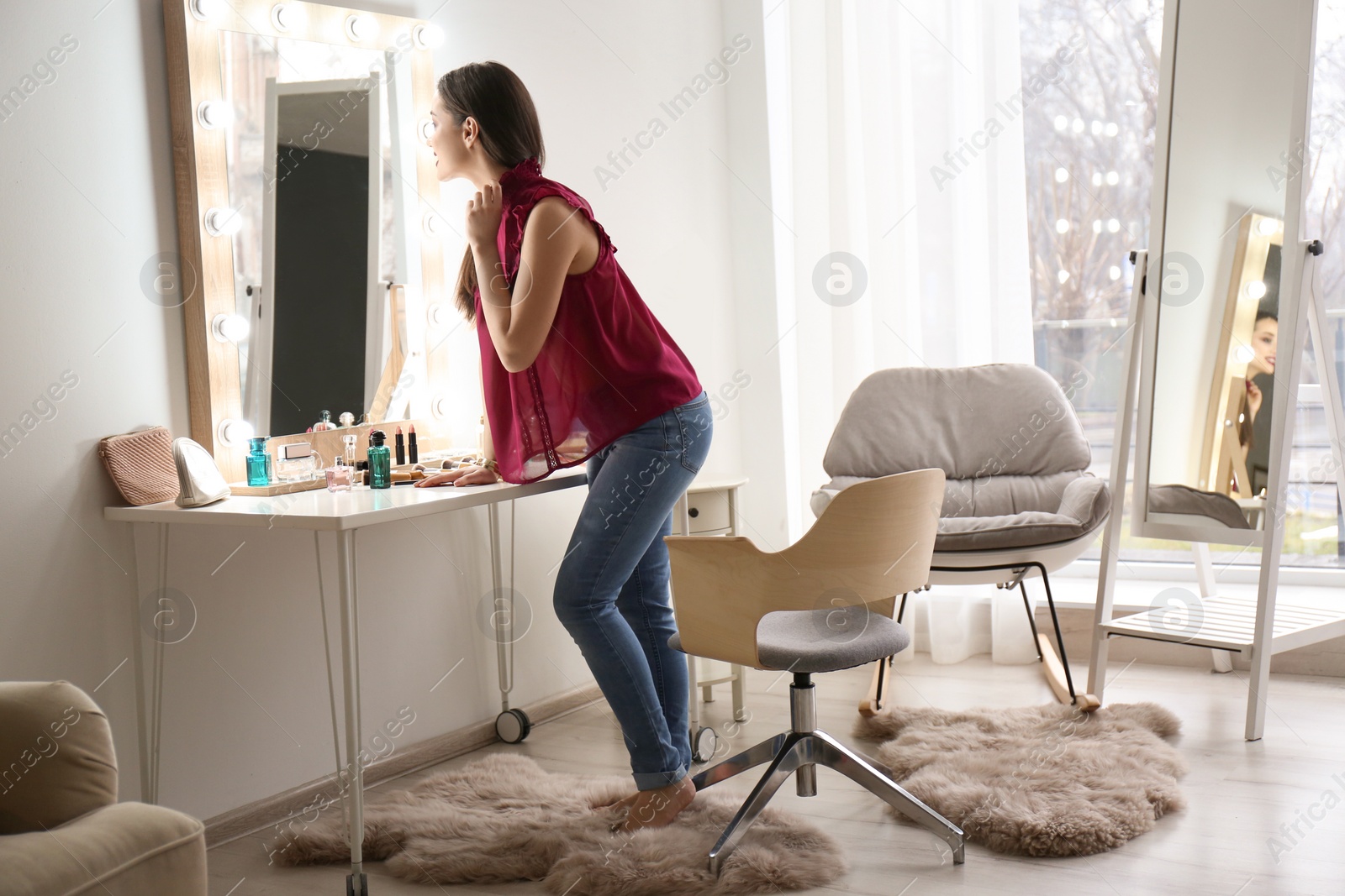 Photo of Portrait of beautiful woman with bright makeup near mirror indoors