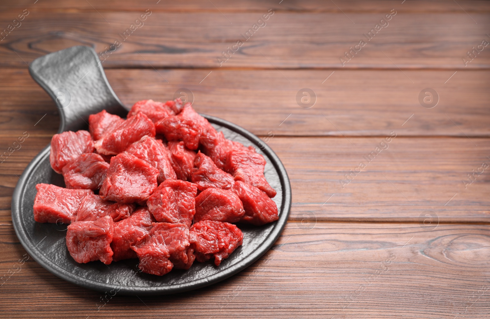 Photo of Pieces of raw beef meat on wooden table. Space for text