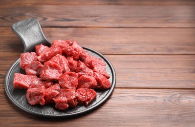 Photo of Pieces of raw beef meat on wooden table. Space for text