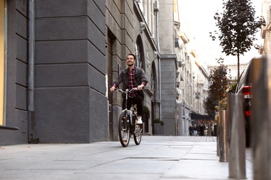 Handsome happy man riding bicycle on city street