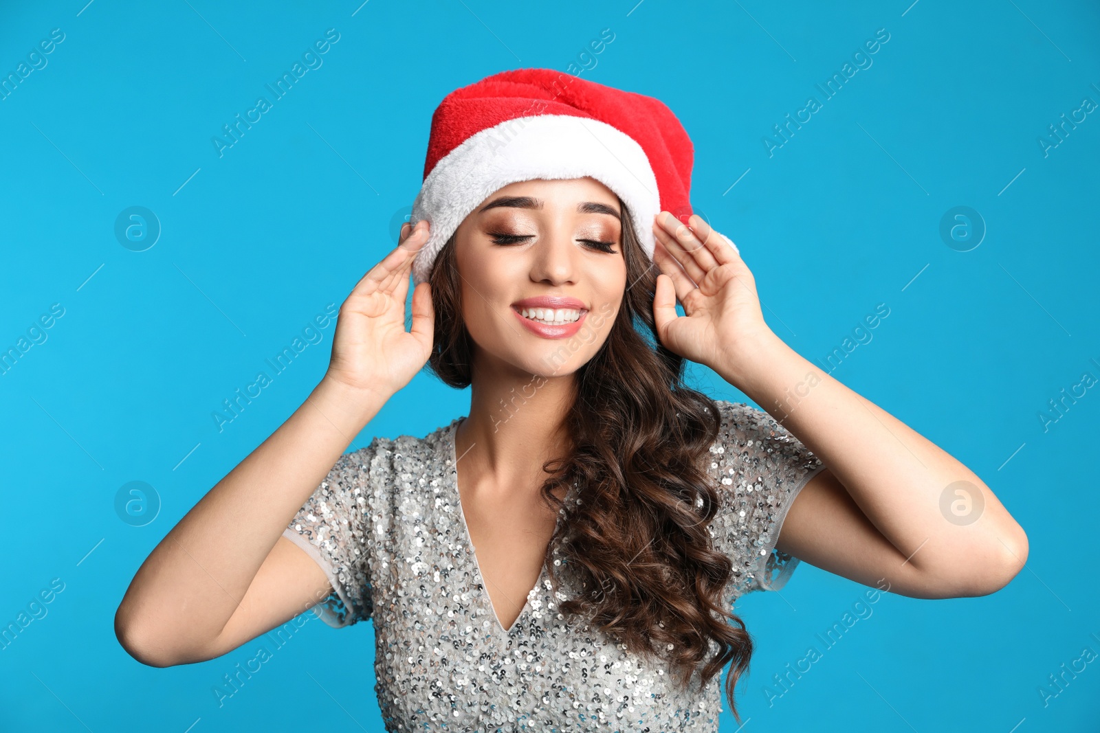 Photo of Beautiful woman in Santa hat on blue background. Christmas party