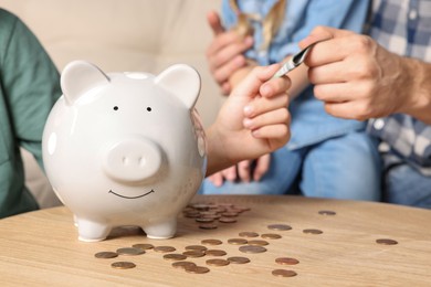 Photo of Family with money and piggy bank at home, closeup