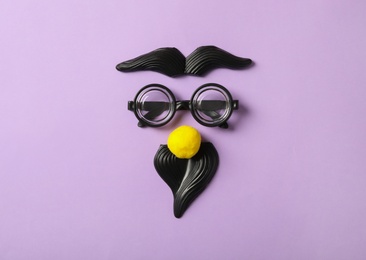 Photo of Funny face made with clown's accessories on lilac background, flat lay