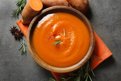 Photo of Flat lay composition with bowl of tasty sweet potato soup on grey background