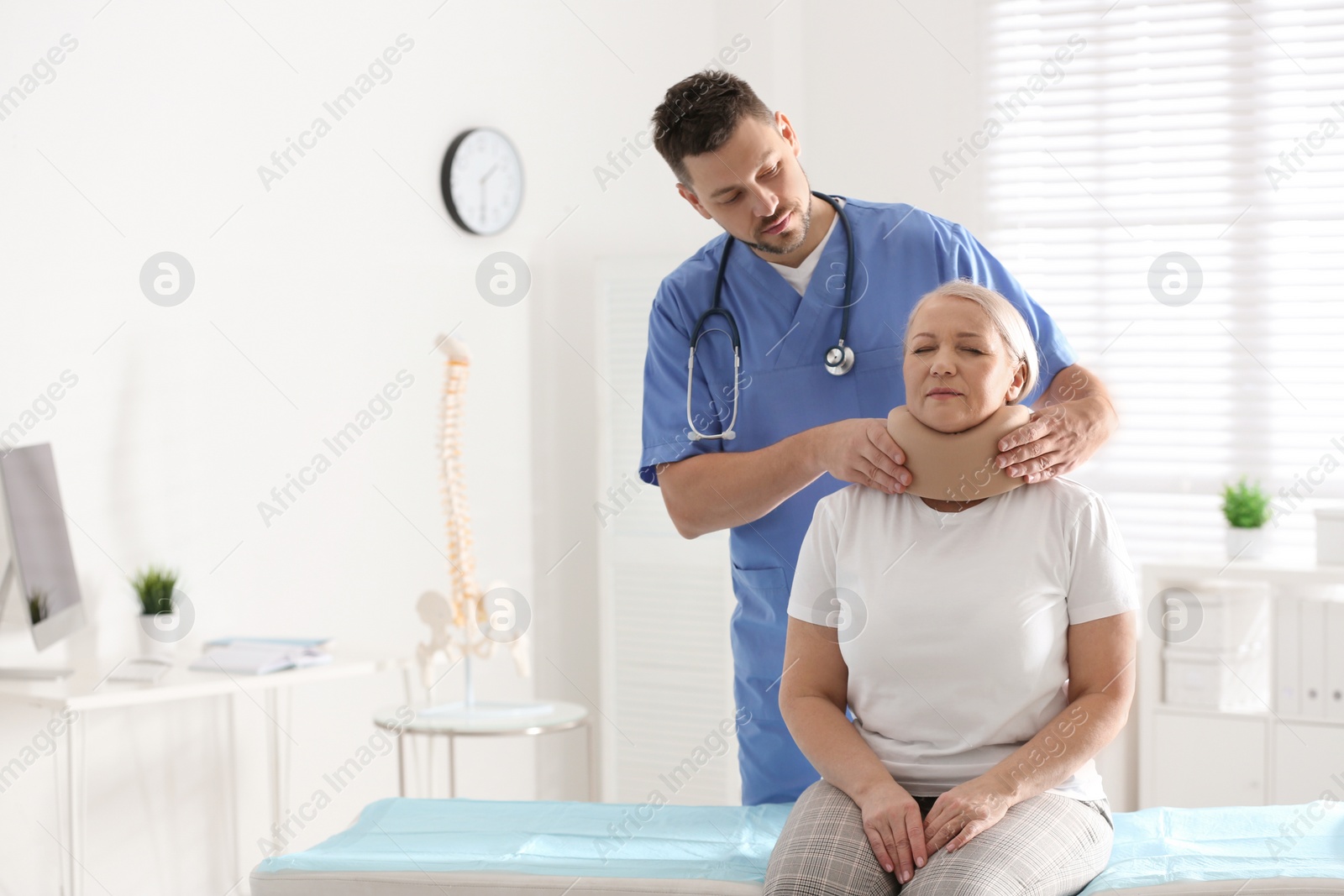 Photo of Orthopedist applying cervical collar onto patient's neck in clinic