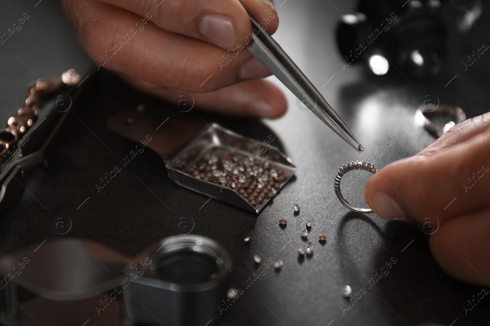 Photo of Male jeweler examining diamond ring in workshop, closeup view