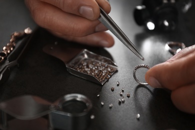 Male jeweler examining diamond ring in workshop, closeup view