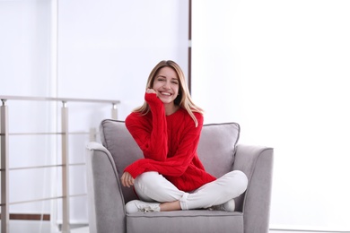 Photo of Attractive young woman sitting in armchair indoors. Space for text