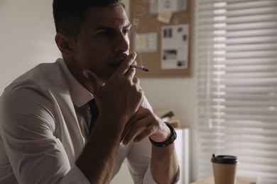 Professional detective smoking cigarette in his office, closeup
