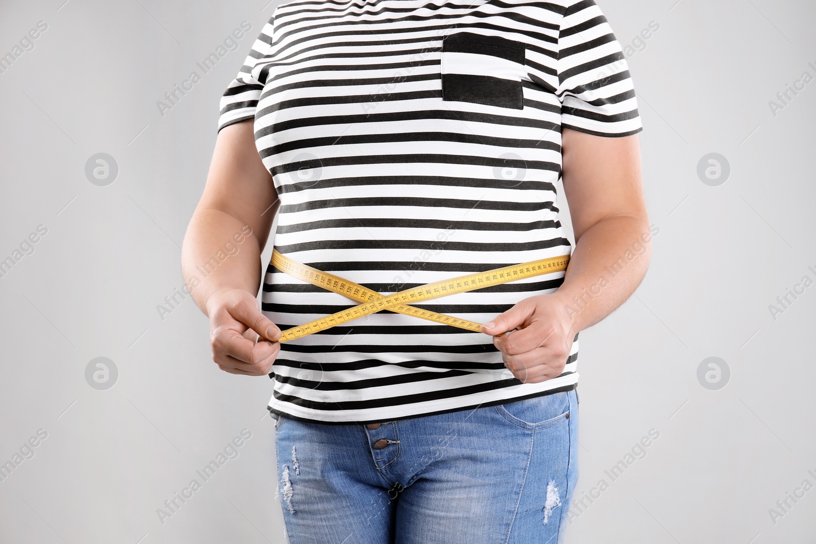 Photo of Fat woman with measuring tape on grey background, closeup. Weight loss