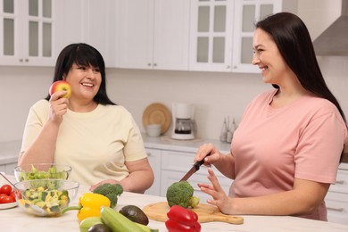 Photo of Happy overweight women cooking together in kitchen