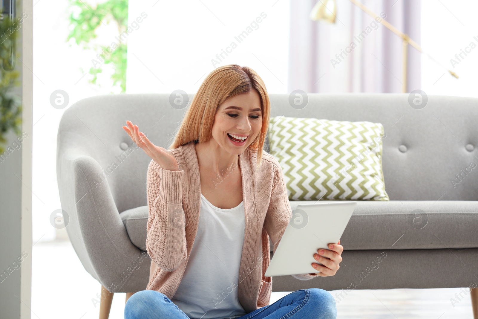 Photo of Woman using tablet for video chat in living room