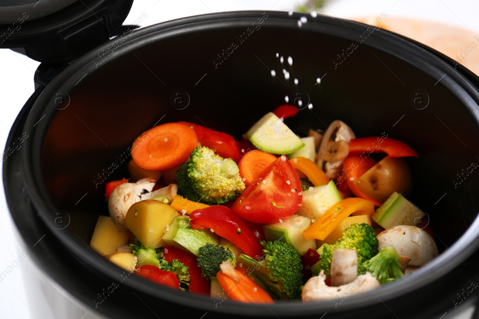 Photo of Adding salt to vegetables in multi cooker, closeup