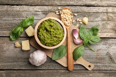 Photo of Tasty pesto sauce, basil, pine nuts, cheese and garlic on wooden table, top view