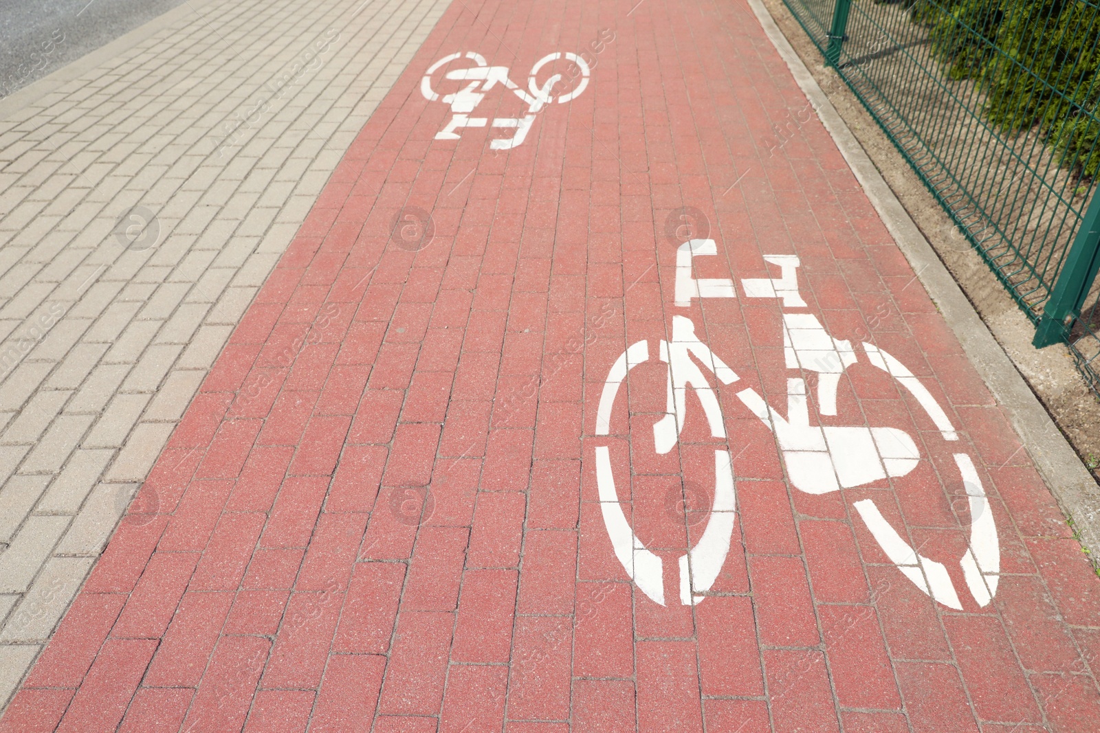 Photo of View of red bicycle lane with white signs on pavement
