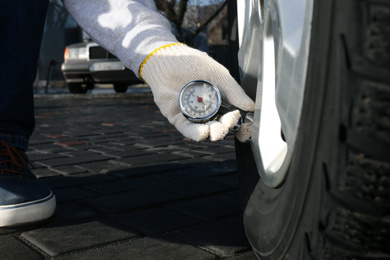 Mechanic checking tire air pressure at car service, closeup