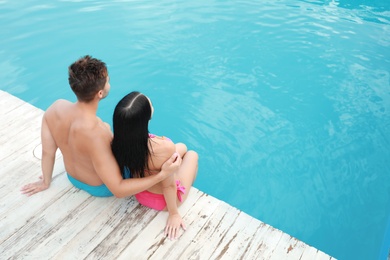 Photo of Woman in bikini with boyfriend near outdoor pool. Young couple