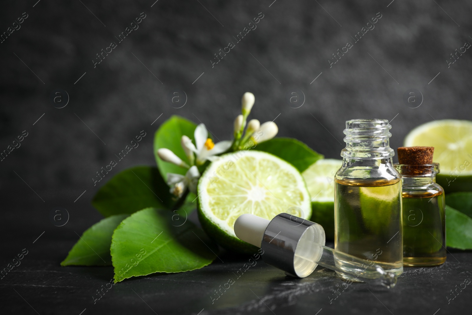 Photo of Bottles of citrus essential oil on black table. Space for text