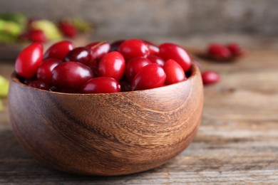 Photo of Fresh ripe dogwood berries in bowl on wooden table, closeup