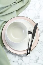 Photo of Clean plates, bowl and cutlery on white marble table, top view