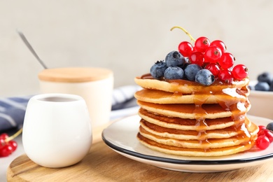Photo of Delicious pancakes with fresh berries and syrup on table