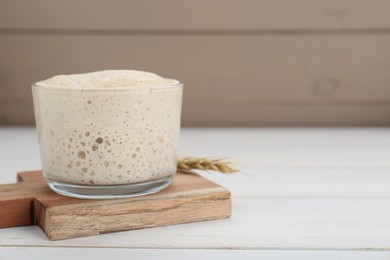 Leaven and ear of wheat on white wooden table, space for text