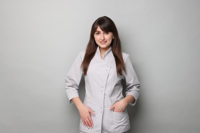 Photo of Cosmetologist in medical uniform on grey background