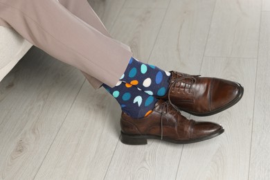 Photo of Man wearing stylish shoes and colorful socks indoors, closeup