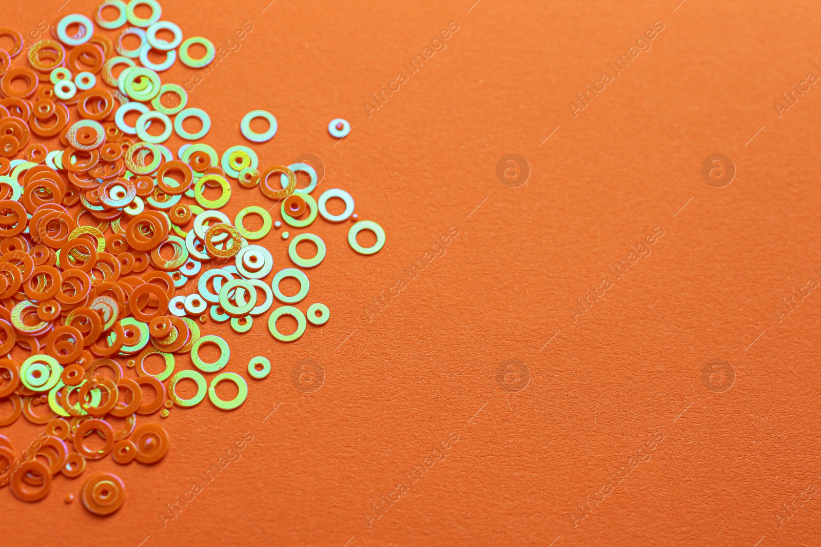 Photo of Shiny bright glitter on orange background. Space for text