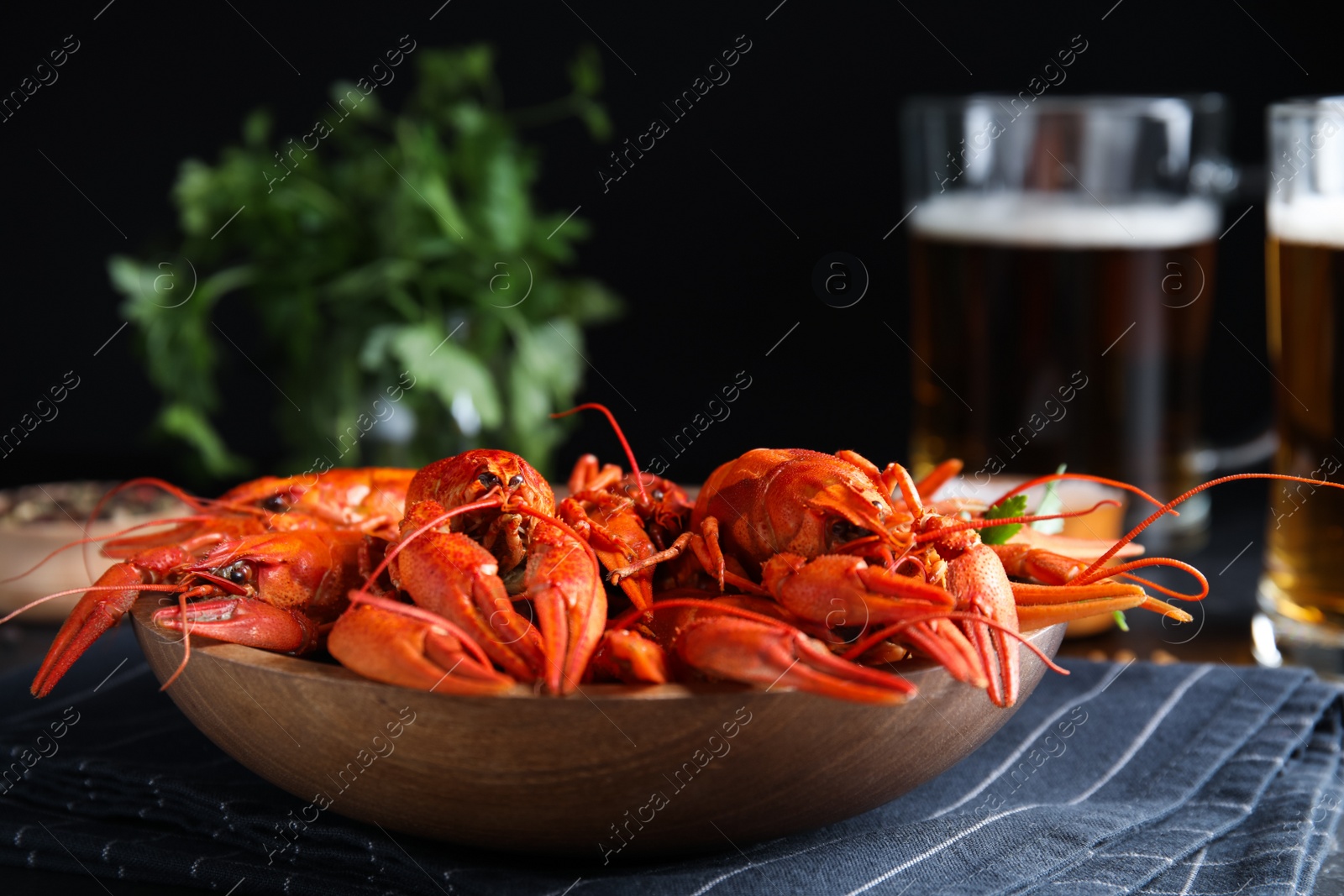 Photo of Delicious red boiled crayfishes on table against black background