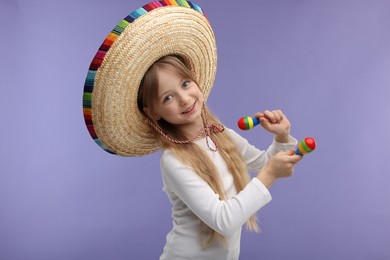 Cute girl in Mexican sombrero hat dancing with maracas on purple background