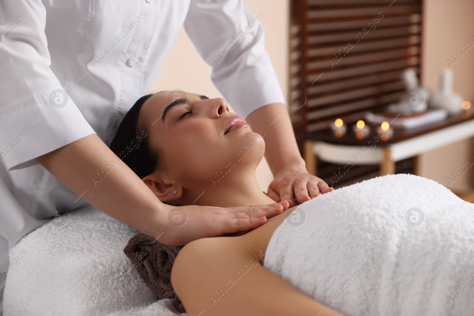 Photo of Young woman enjoying professional massage in spa salon