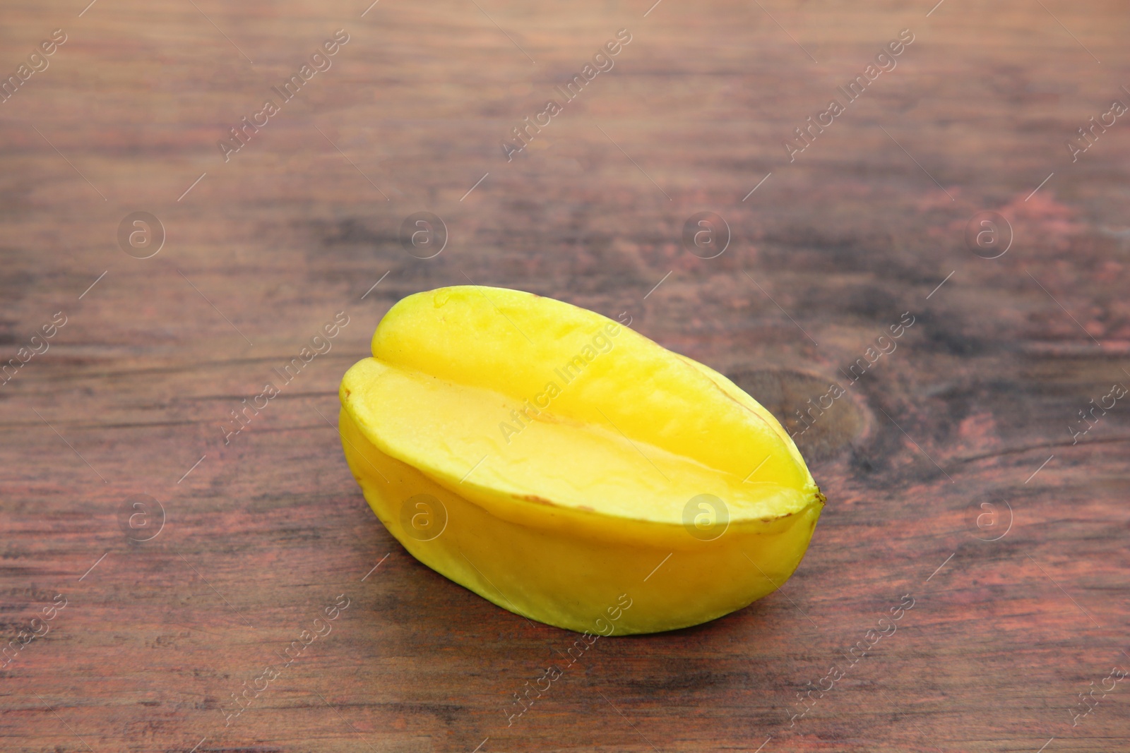 Photo of One delicious ripe carambola on wooden table