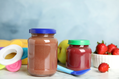 Healthy baby food in jars and fresh ingredients on white marble table