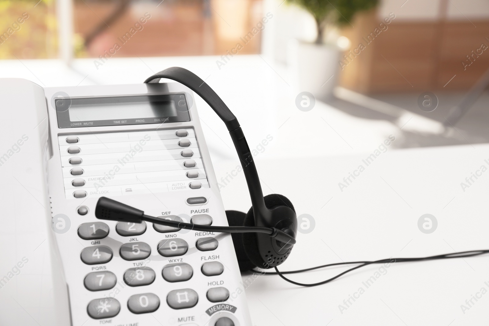 Photo of Headset and desk phone on table, space for text. Technical support concept