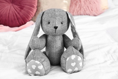 Cute stuffed toy rabbit on comfortable bed in child's room interior