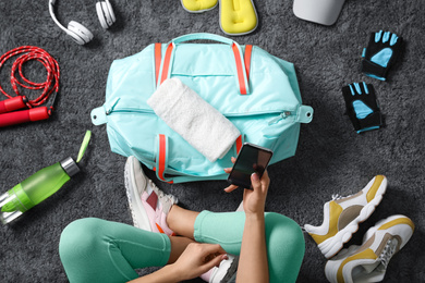 Photo of Woman with bag and sports items on grey carpet, top view