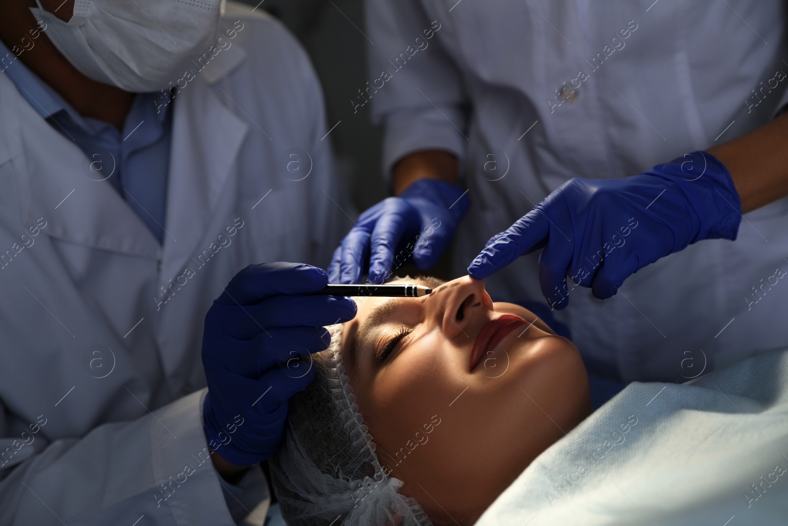 Photo of Doctor and nurse preparing female patient for cosmetic surgery in clinic