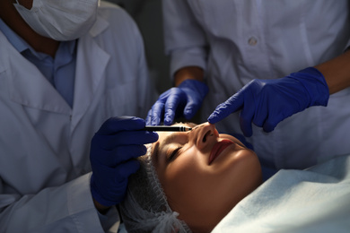 Doctor and nurse preparing female patient for cosmetic surgery in clinic