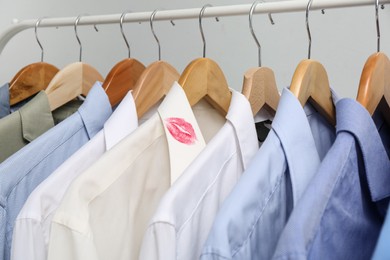 Photo of Men's shirts and one with lipstick kiss mark on rack, closeup